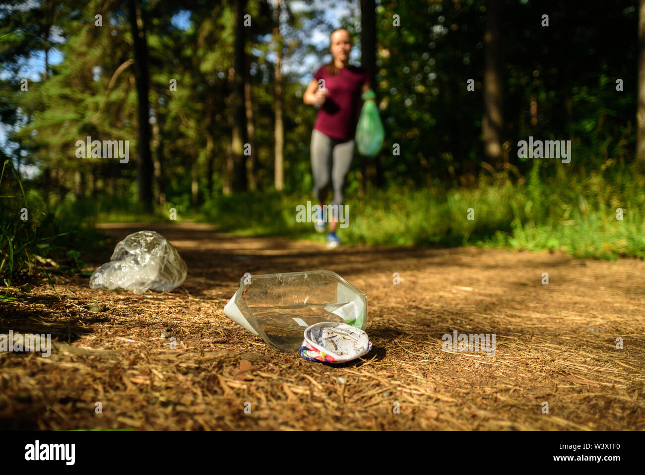 Woman jogging avec sac à déchets en forêt. La collecte des ordures. Concept Plogging Banque D'Images