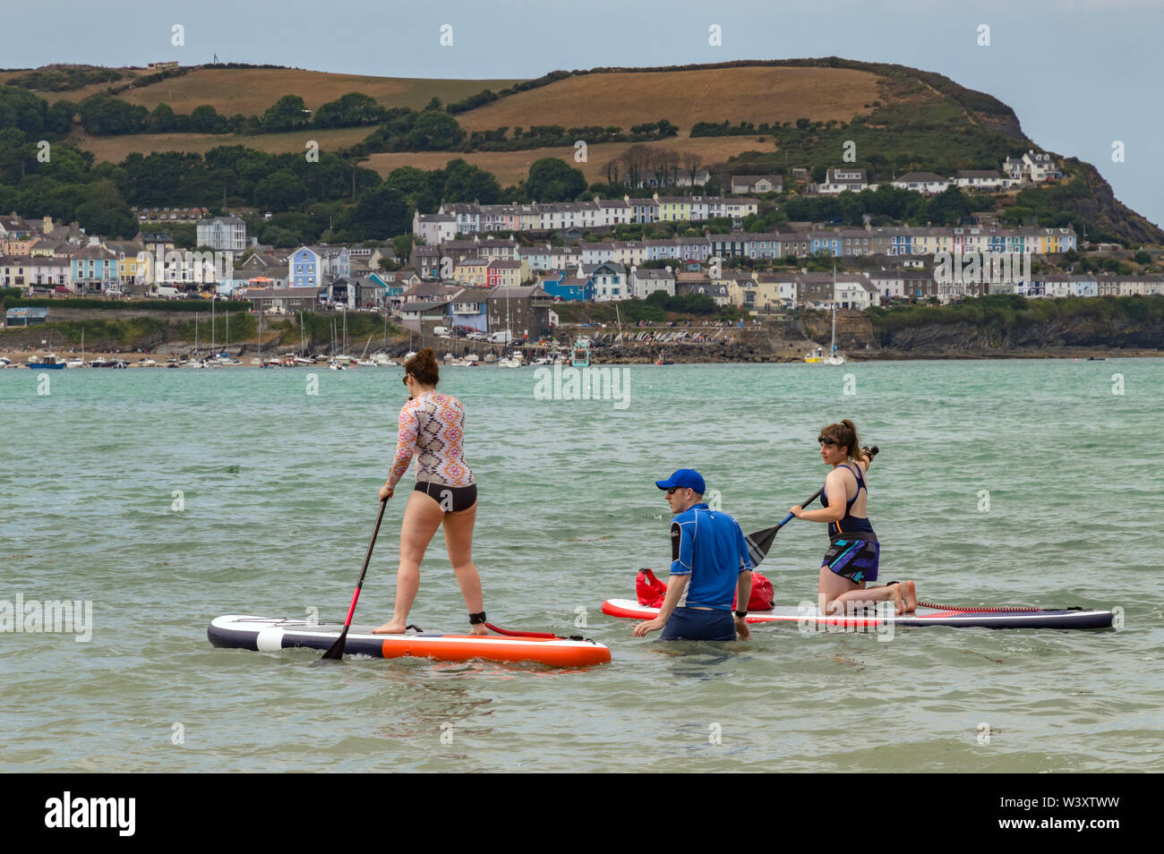 Les jeunes femmes apprennent à paddle board à New Quay, Ceredigion, pays de Galles Banque D'Images