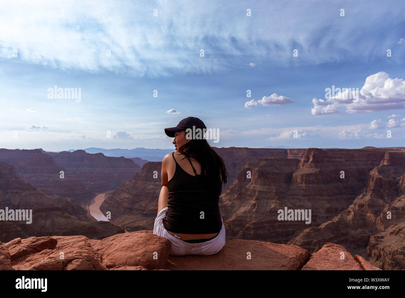 Une fille assise sur une falaise en regardant le grand canyon Arizona USA Banque D'Images