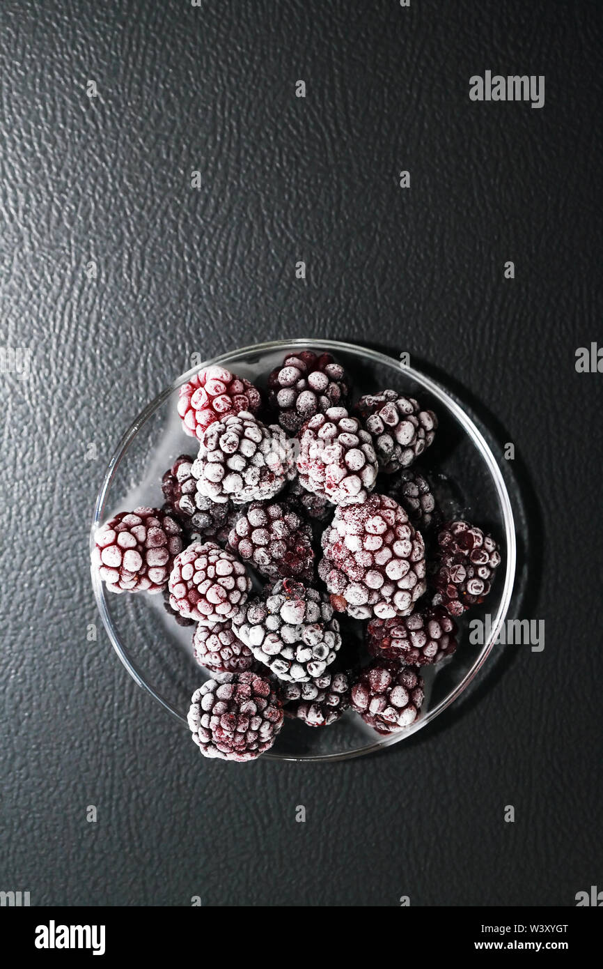 Avec soucoupe tas de fruits congelés black berry sur fond sombre Banque D'Images