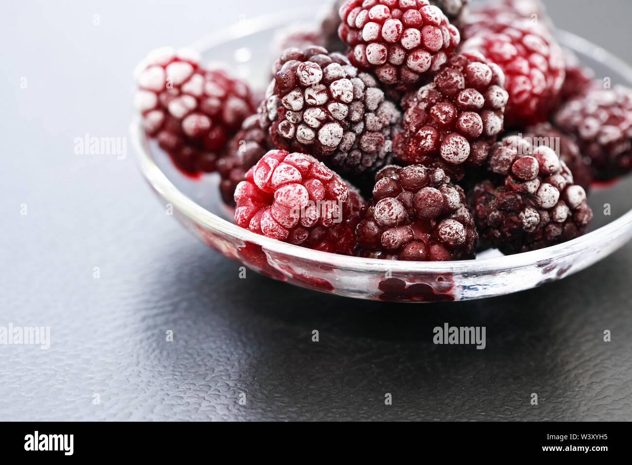 Avec soucoupe tas de fruits congelés black berry sur fond sombre Banque D'Images