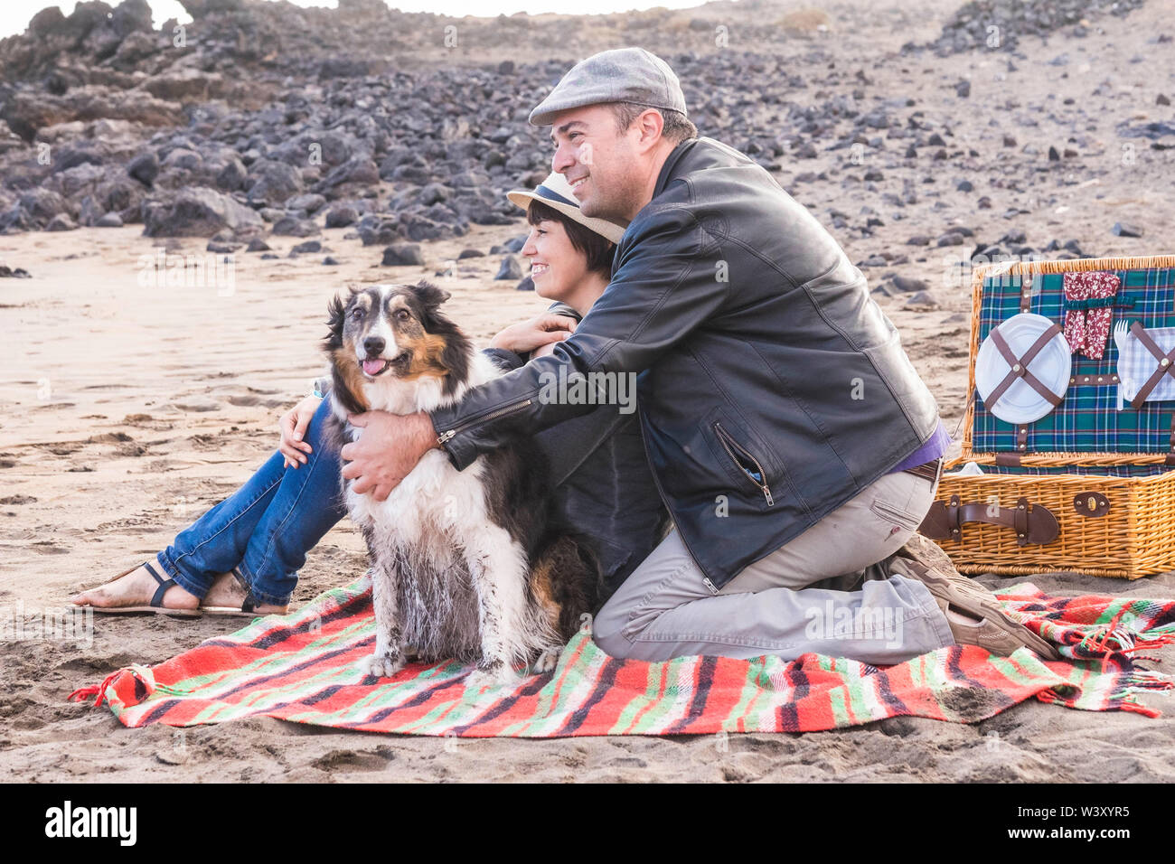 Famille adultes heureux les gens à rester ensemble à la plage avec drôle adorable chien sale - le bonheur et l'activité de loisirs de plein air pour l'homme et la femme dans l'amour Banque D'Images
