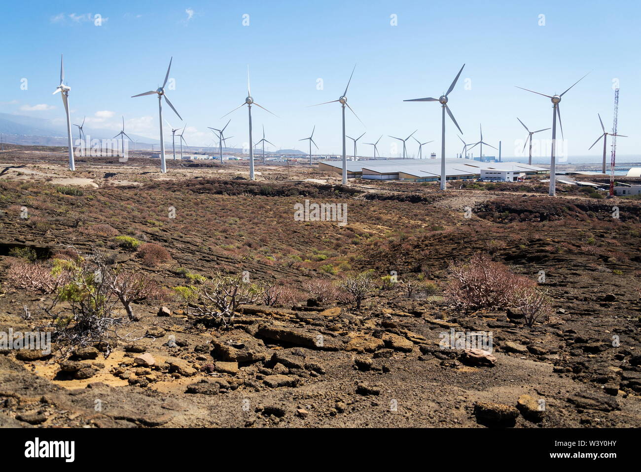 Les turbines éoliennes à blanc avec power station et mer en arrière-plan, paysage aride aux beaux jours de l'été, de l'électricité renouvelable durable concept Banque D'Images