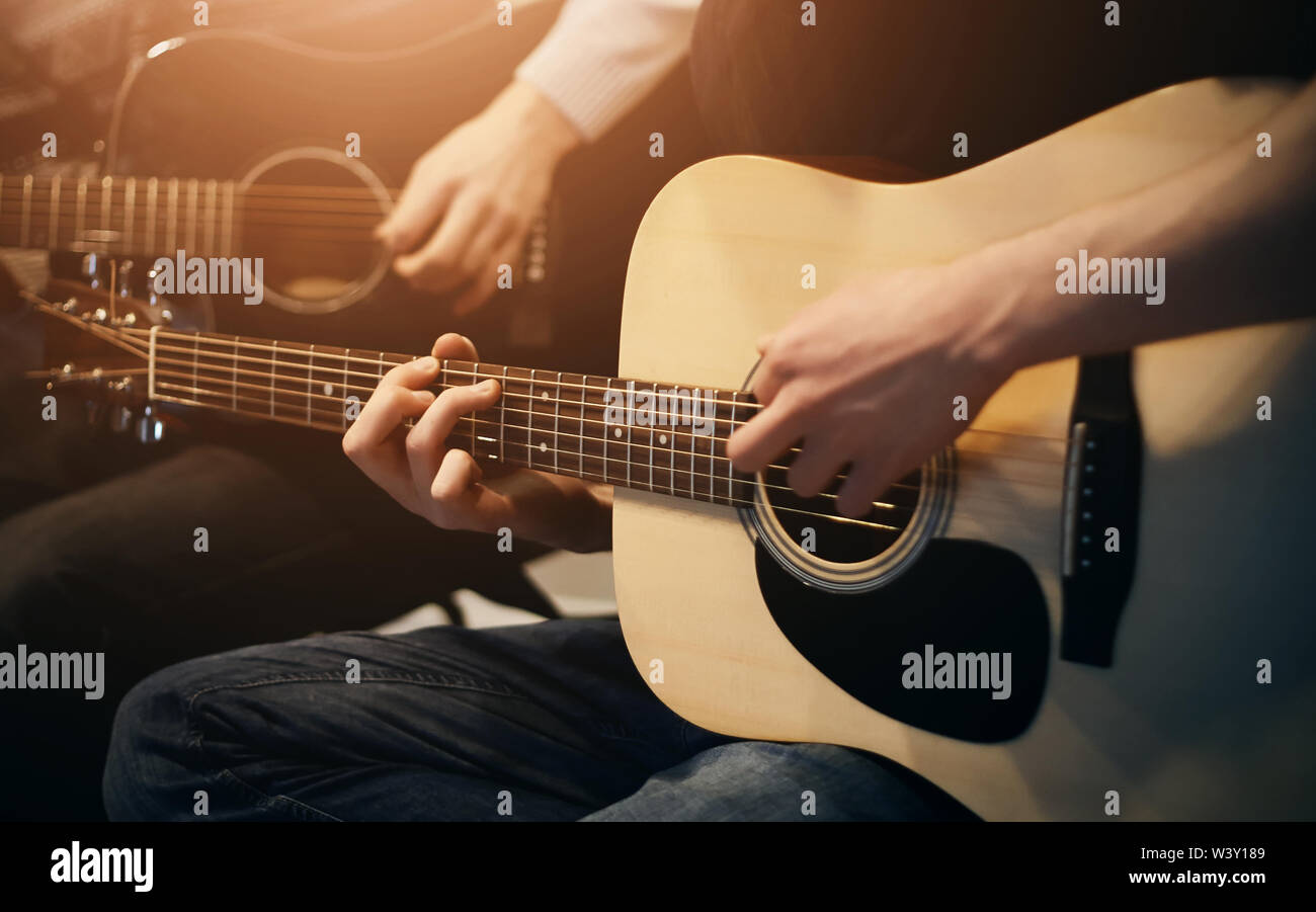 Un duo de deux musiciens qui jouent ensemble sur une belle mélodie de guitares acoustiques lors d'un concert. Ils sont assis, éclairé par la lumière de la lampe. Banque D'Images