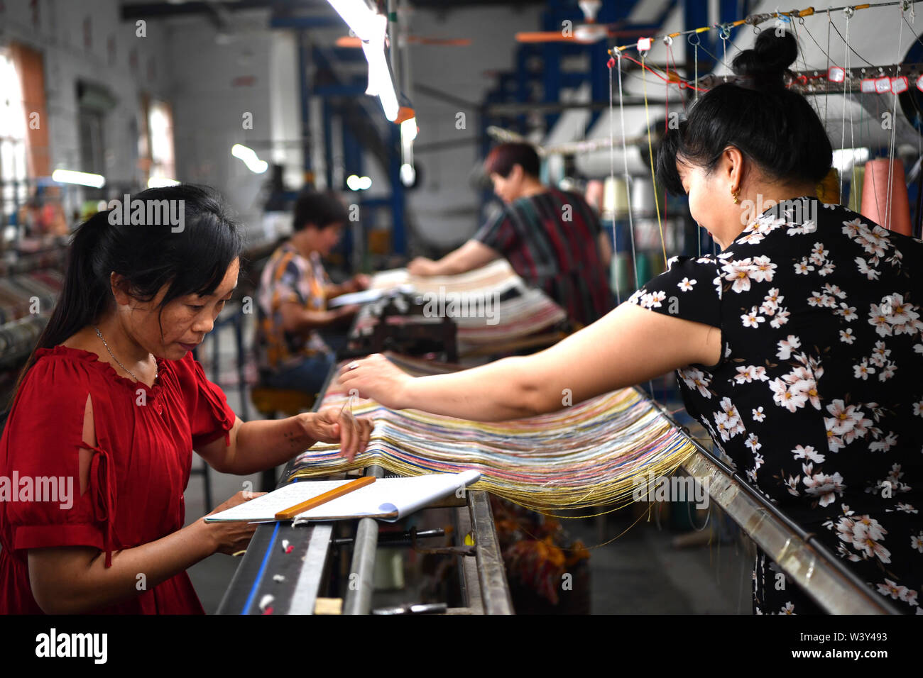 Nanyang, province de Henan en Chine. 17 juillet, 2019. Tapis en soie tissent des travailleurs lors de l'atelier de fabrication artisanale Yuxiang Nanyang Co., Ltd. à Nanyang, province de Henan en Chine centrale, le 17 juillet 2019. Les tapis en soie faite dans le comté de Nanzhao, doté du style persan, ont été exportés dans plus de 30 pays et régions, en stimulant l'économie locale et les revenus des agriculteurs. 22 Shangshan Road Crédit : Li/Xinhua/Alamy Live News Banque D'Images