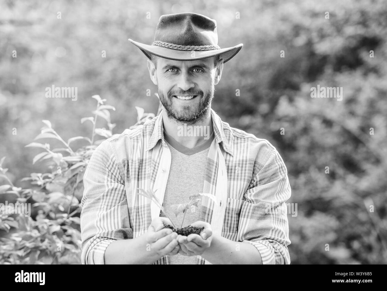 L'homme musclé en chapeau de cowboy ranch Soins des plantes. Travailleur agricole écologique. Le jour de la terre. heureux le jour de la terre. La vie Eco. L'agriculture et de l'agriculture la culture. Le Jardinage. Agriculteur prospère usine de tenir la masse dans les mains. Banque D'Images