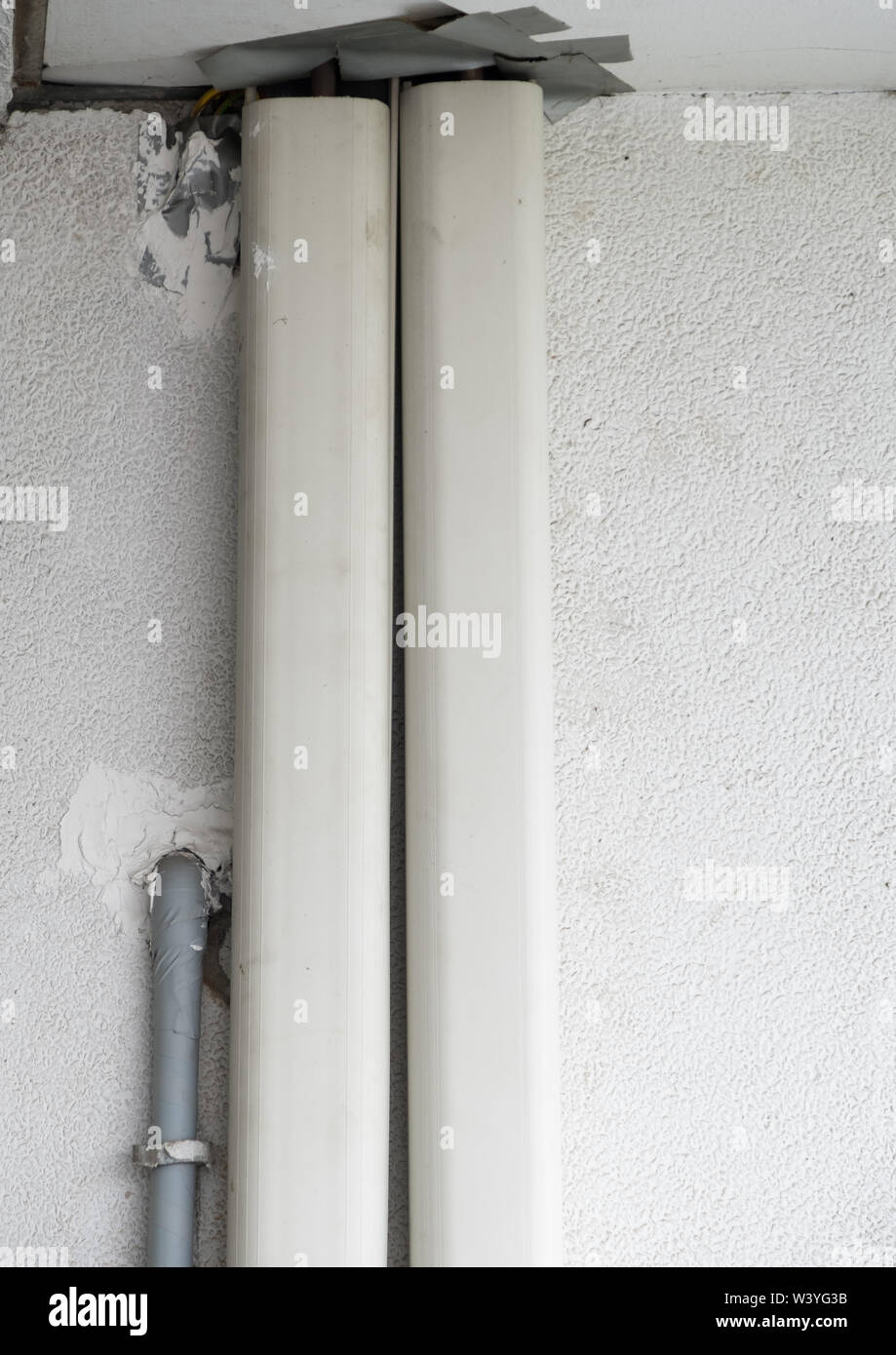 Les tuyaux en plastique couvercle du système de climatisation sur le mur de béton blanc de l'office. Banque D'Images