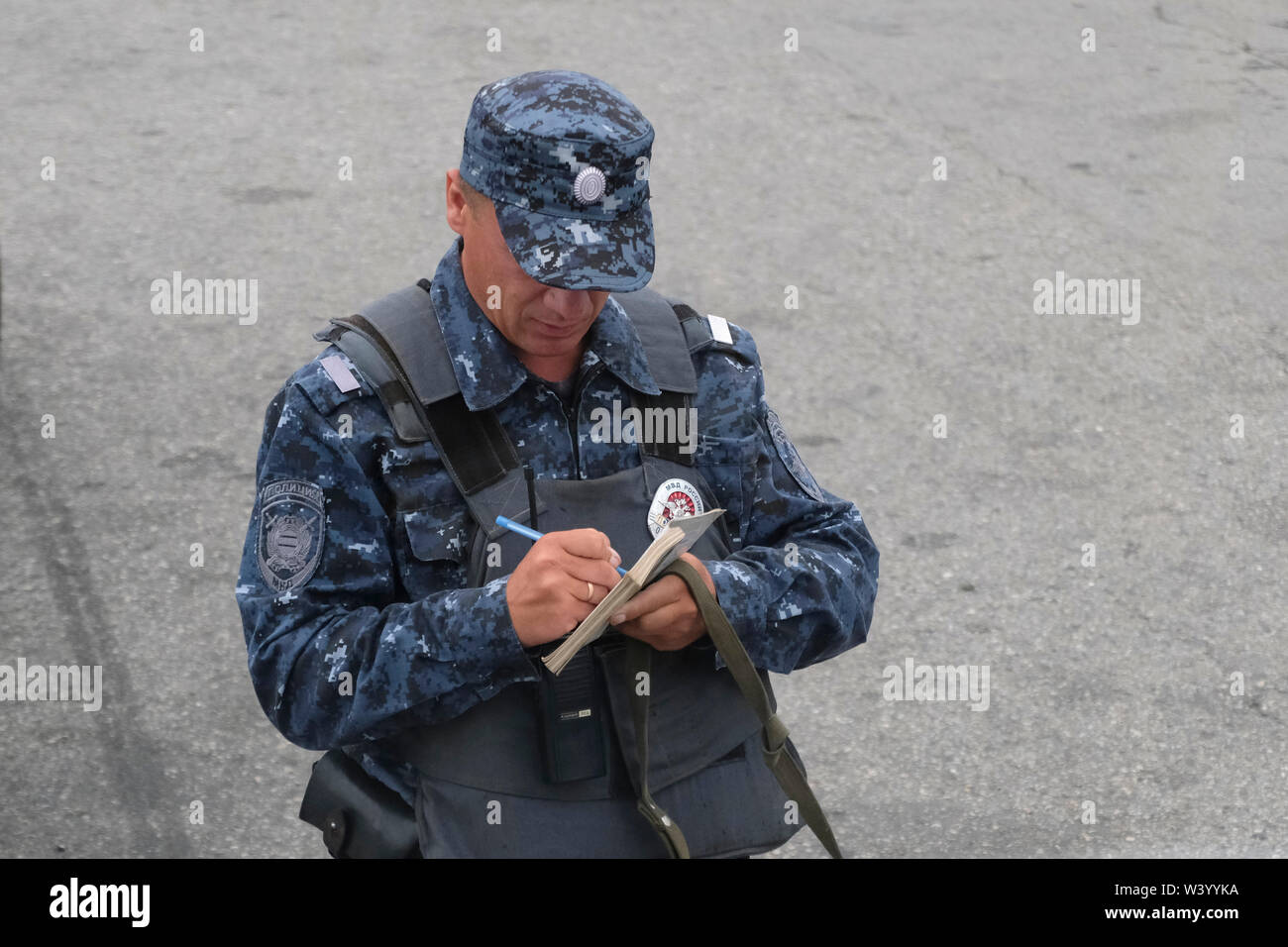 Un agent de police portant des flack jacket écrit le numéro de la plaque d'une voiture à un poste de contrôle de la frontière entre la République d'Ingouchie et de la République d'Ossétie du Nord dans le District fédéral du Caucase du Nord de la Russie Banque D'Images