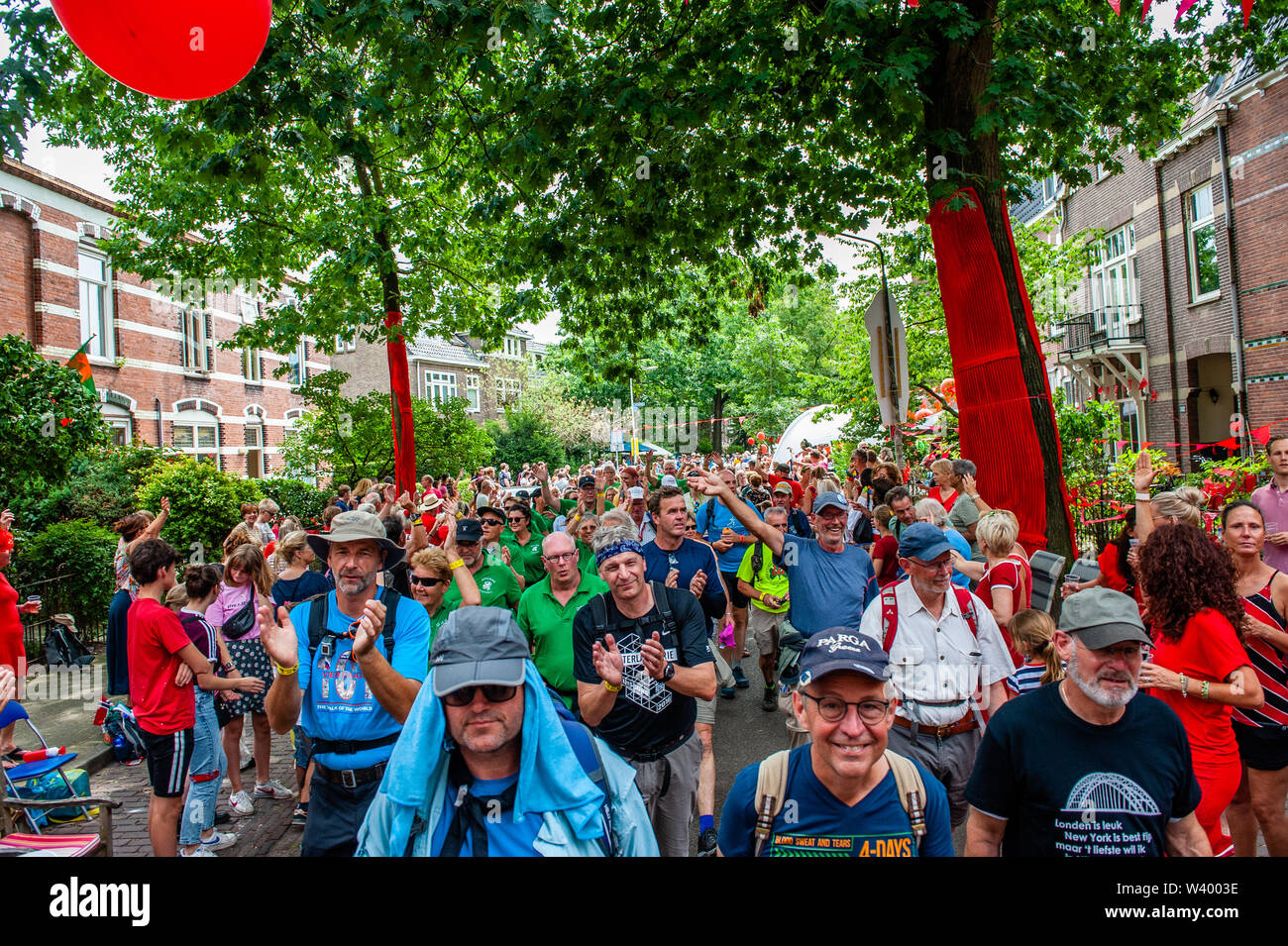 Les participants à pied dans un quartier décoré de rouge pendant le troisième jour.puisque c'est la plus grande épreuve de marche de plusieurs jours, les quatre jours le mois de mars est considéré comme le premier exemple d'esprit sportif et les liens entre militaires et civils et les femmes de nombreux pays différents. Le troisième jour à vélo est bien connue en raison de ses sept collines, qui sont toujours un défi pour les marcheurs. Certains des quartiers de Nijmegen célébrer l'arrivée des promeneurs en décorant les façades de maisons et beaucoup de parties, ce qui est toujours un très bon accueil au parti Banque D'Images