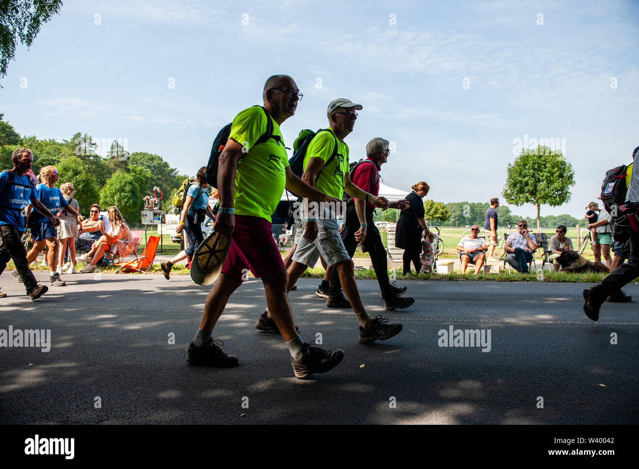 Trois hommes à pied au cours de la troisième journée.puisque c'est la plus grande épreuve de marche de plusieurs jours, les quatre jours le mois de mars est considéré comme le premier exemple d'esprit sportif et les liens entre militaires et civils et les femmes de nombreux pays différents. Le troisième jour à vélo est bien connue en raison de ses sept collines, qui sont toujours un défi pour les marcheurs. Certains des quartiers de Nijmegen célébrer l'arrivée des promeneurs en décorant les façades de maisons et beaucoup de parties, ce qui est toujours un très bon accueil aux participants. Banque D'Images