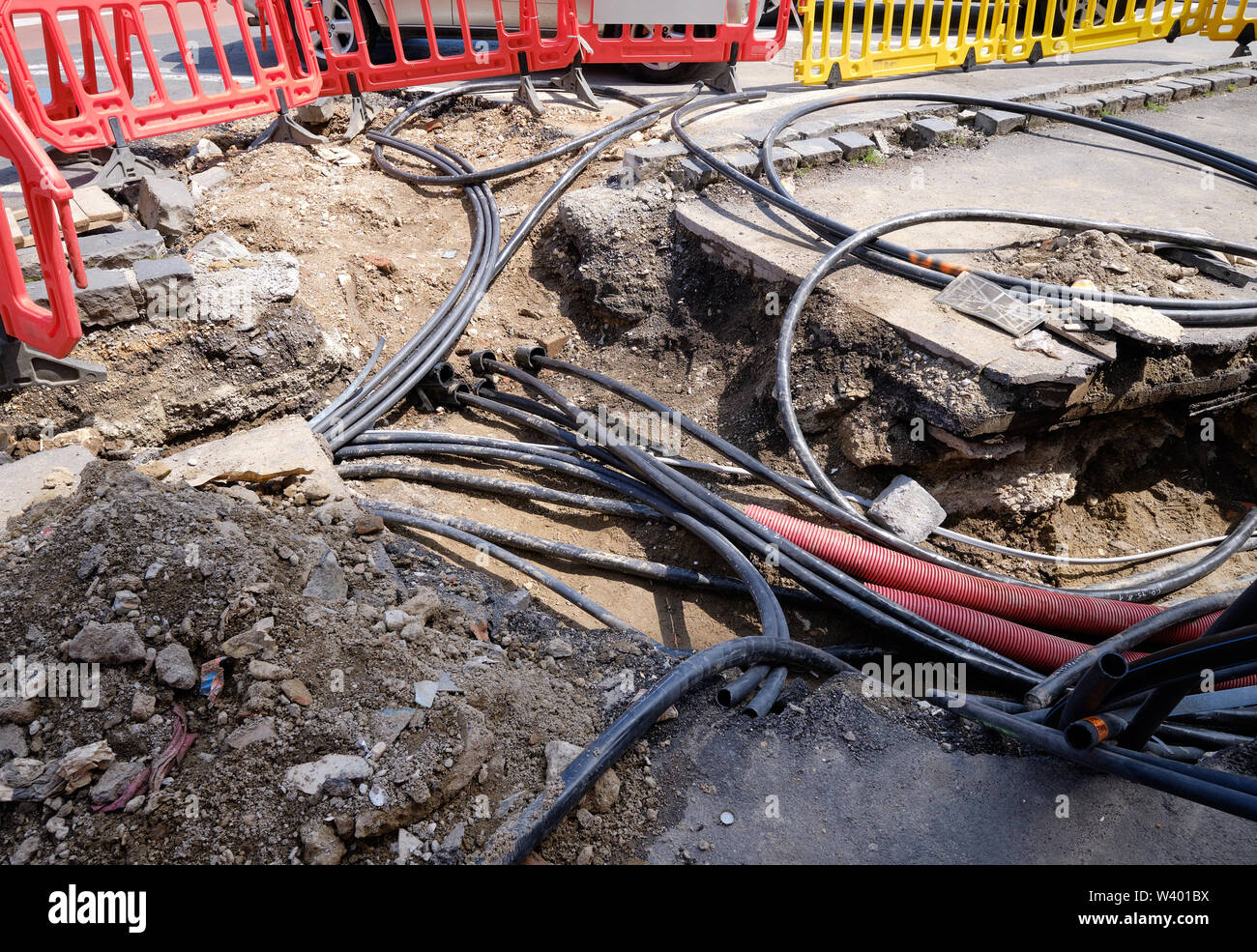 Creusé le trottoir révélant des fils dans des tubes de protection. Construction de lignes électriques ou de câbles de télécommunication, construction de connexions de réseaux optiques Banque D'Images
