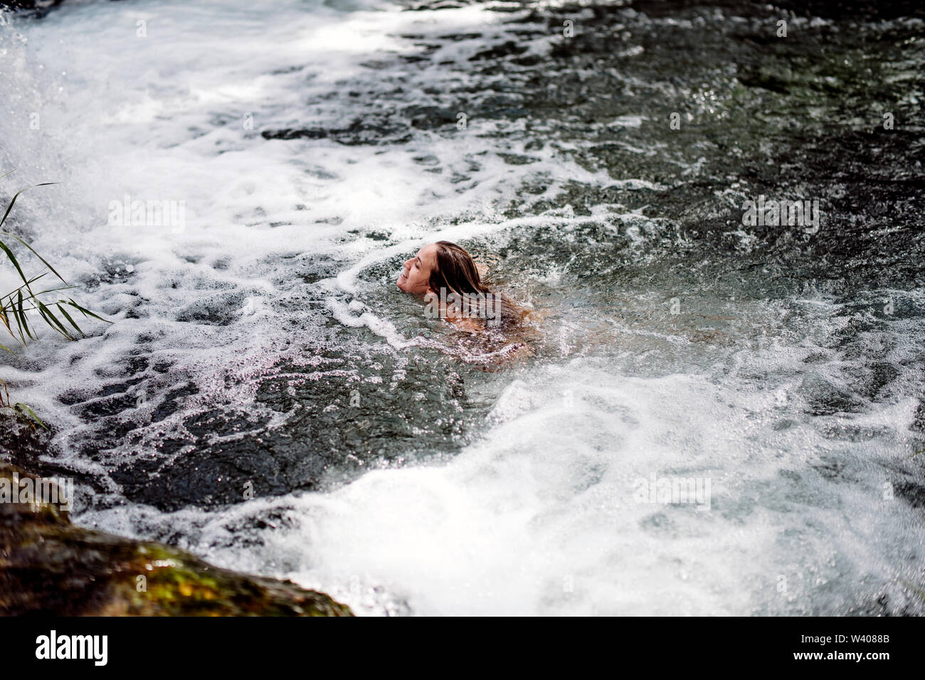 Blonde woman bathing in belle rivière Cascade. Banque D'Images