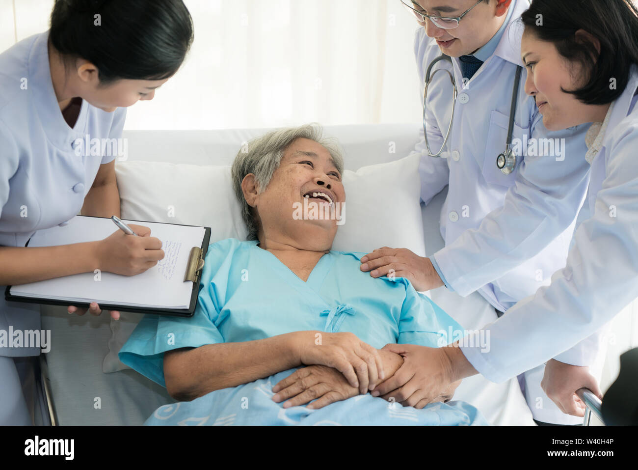 Asian medical équipe de médecins d'examiner et de parler aux personnes âgées Asie femme patient, les soins de personnes de prendre note sur le presse-papiers à l'hôpital. Banque D'Images