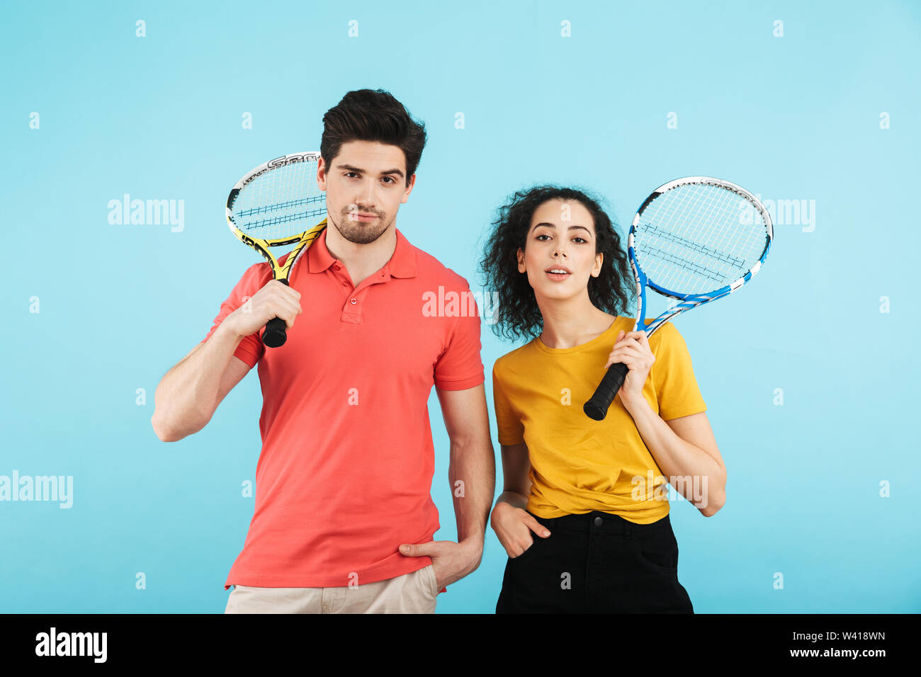 Cheerful young couple isolés sur fond bleu, jouer au tennis Banque D'Images