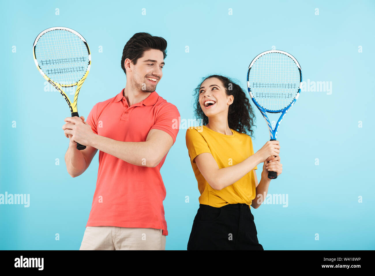 Cheerful young couple isolés sur fond bleu, jouer au tennis Banque D'Images