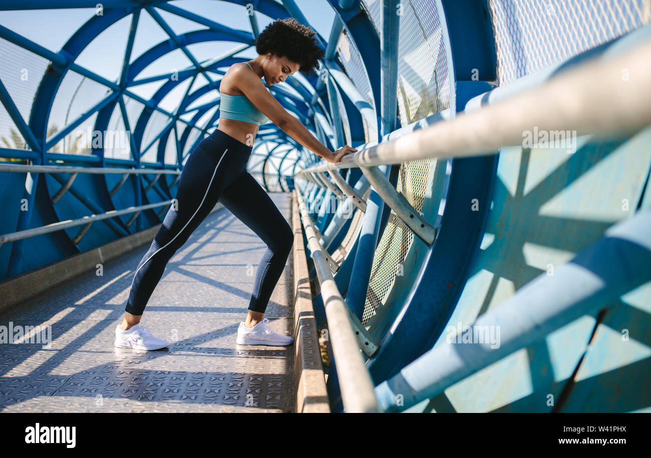 Woman doing stretching remise en forme avec le soutien de garde-corps de pont. Athlète féminin de faire des étirements. Banque D'Images