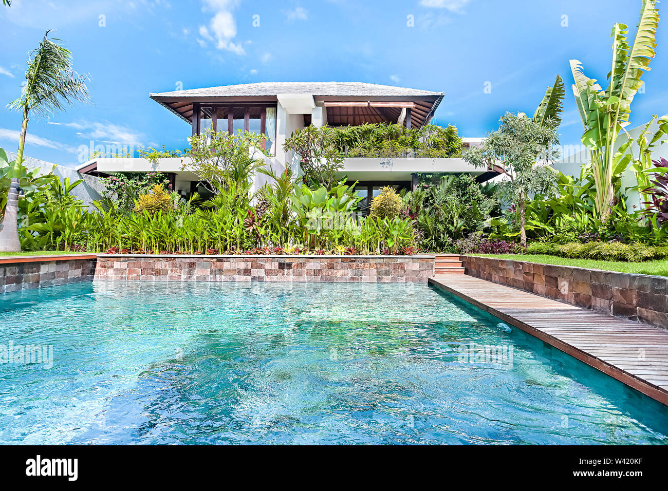 L'eau bleu moderne piscine libre avec un jardin de plantes vertes et d'une maison de luxe Banque D'Images
