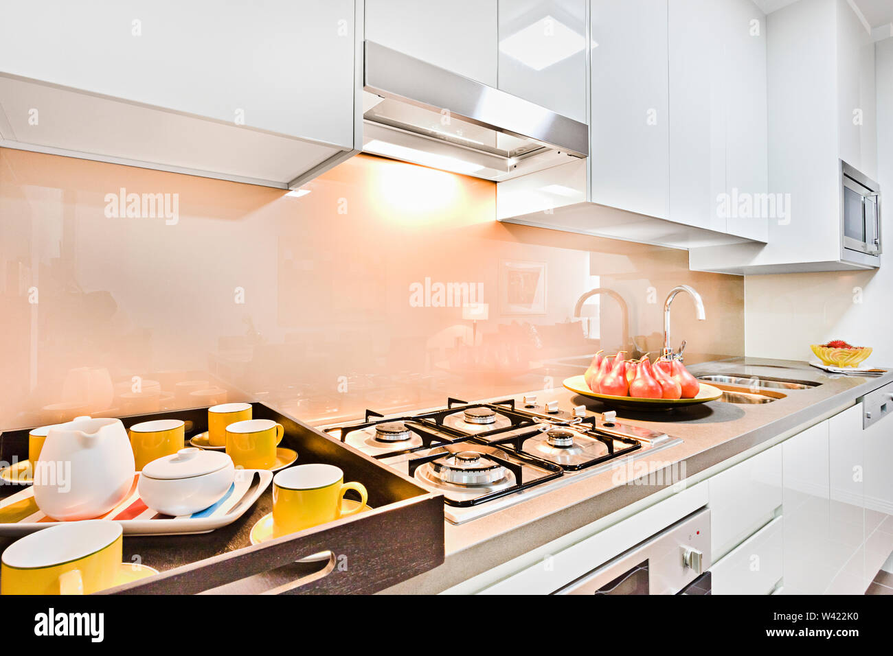 Cher des articles de cuisine sur pantry placard près de l'évier en céramique,  tasses et assiettes ont sur la table de cuisson, four et cuisinière à gaz  libre avec les couleurs, nettoyer