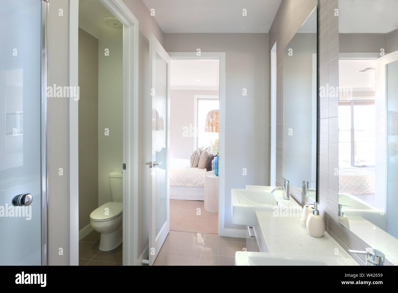 Libre de grands miroirs sur le mur près de l'eau du robinet et évier blanc avec bouteille de savon liquide, la cuvette de toilette isolé dans une pièce. Il y a un moyen de le Banque D'Images