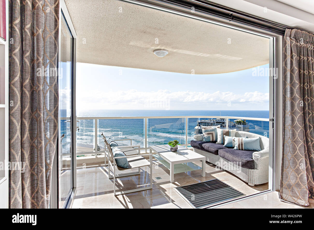 Un balcon avec vue sur la plage avec un coin salon confortable et un centre de table Banque D'Images