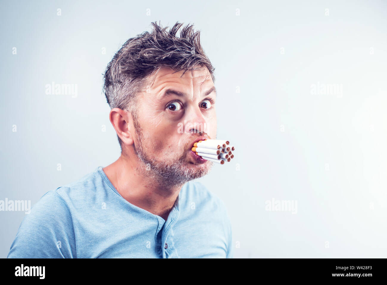 Jeune homme avec beaucoup de cigarettes dans sa bouche Photo Stock