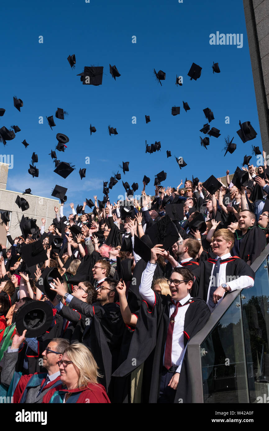 L'enseignement supérieur au Royaume-Uni - les élèves qui réussissent à la remise des diplômes à l'université d'Aberystwyth, après avoir reçu leur diplôme, jetant leurs chapeaux conseil mortier dans l'air à l'occasion . Juillet 2019 Banque D'Images