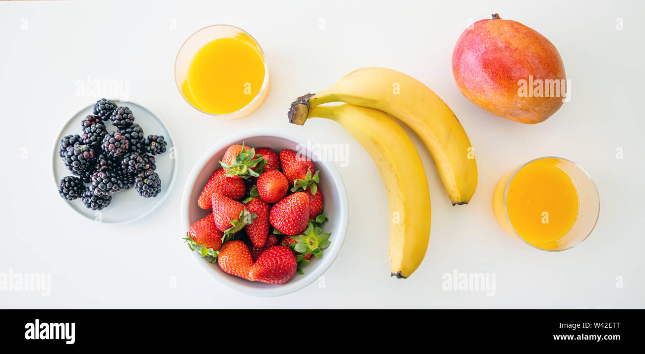 Fruits frais et jus d'orange isolé sur blanc. Petit-déjeuner sain pour deux. La banane, fraise, mûre et de mangue. Vue d'en haut Banque D'Images