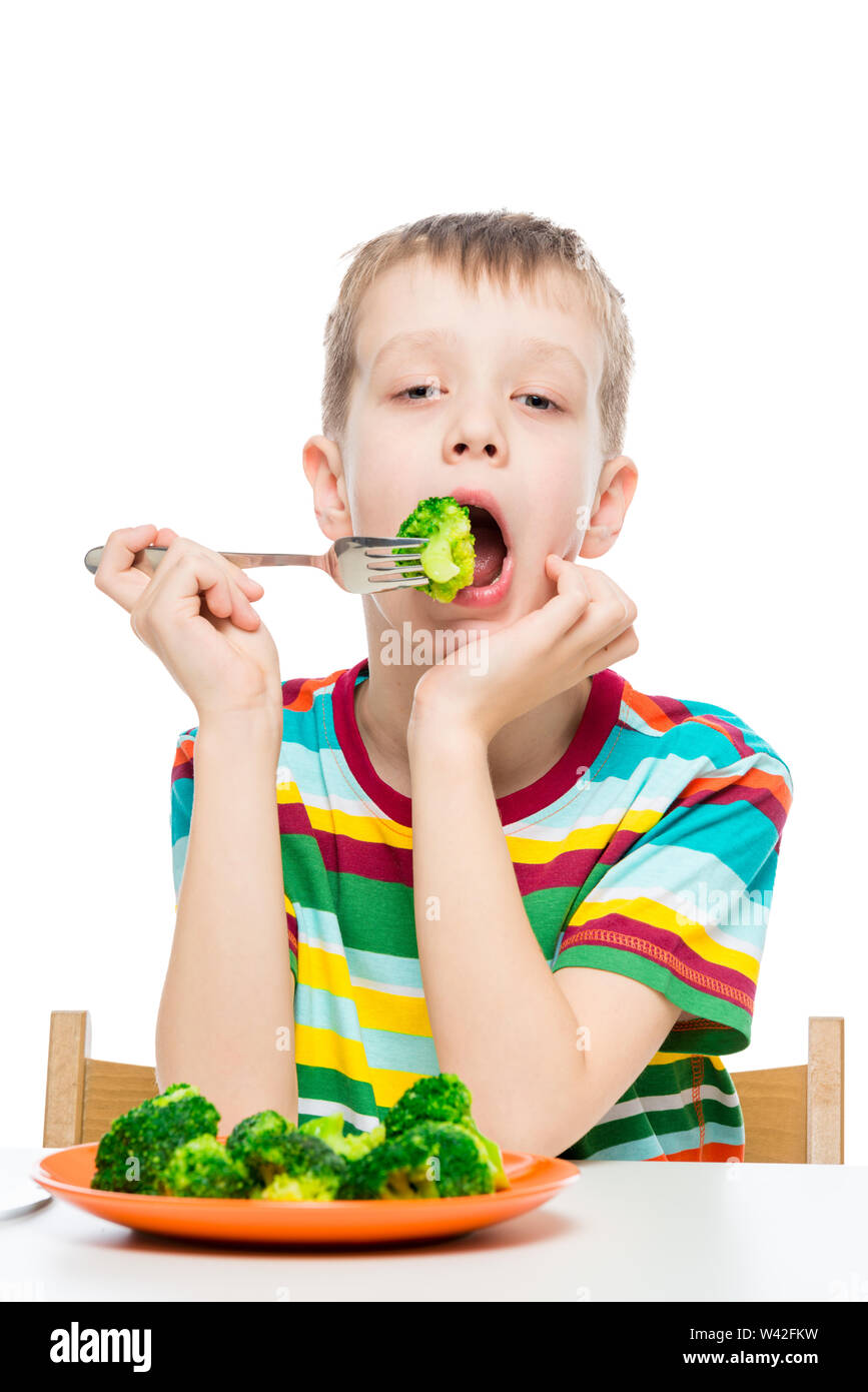 Portrait vertical d'un garçon qui a un régime alimentaire, un enfant mange le brocoli sur fond blanc Banque D'Images
