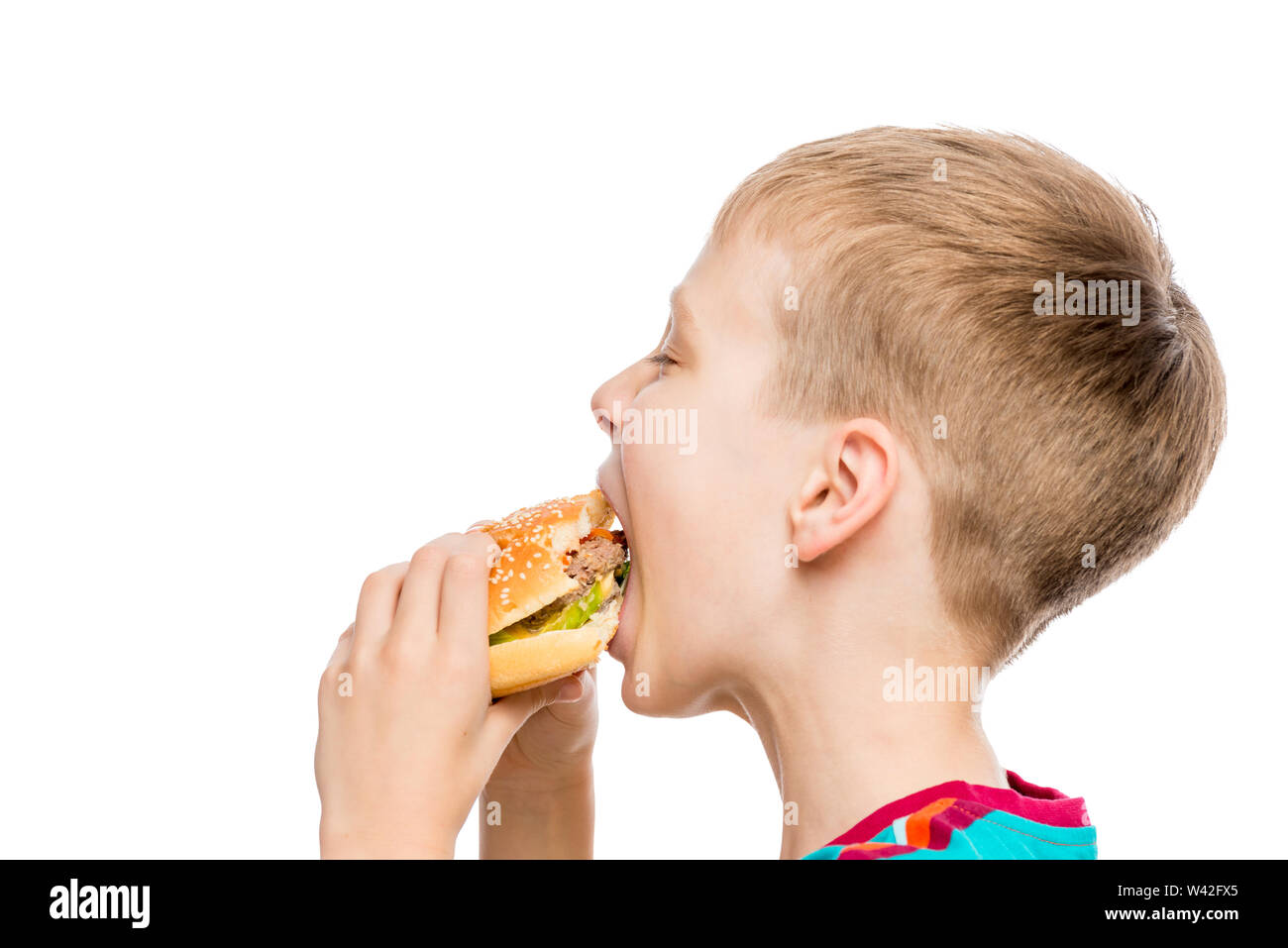 Closeup portrait of a Boy affamé avec un hamburger isolé sur fond blanc Banque D'Images