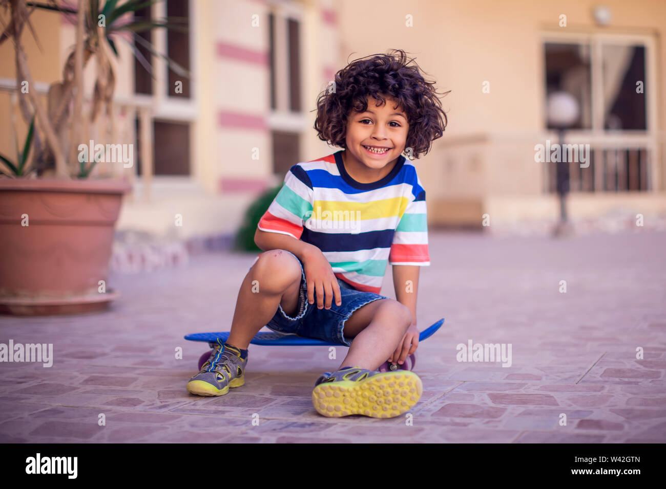 Petit Garcon Aux Cheveux Boucles Avec Une Planche A Roulettes Les Enfants Et De Divertissement Concept Photo Stock Alamy