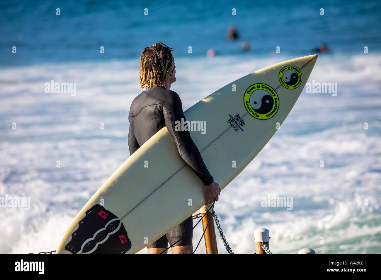 Surfeur, homme portant sa planche de surf prêt pour un après-midi de surf sur les plages du nord de Sydney, Nouvelle-Galles du Sud, Australie Banque D'Images