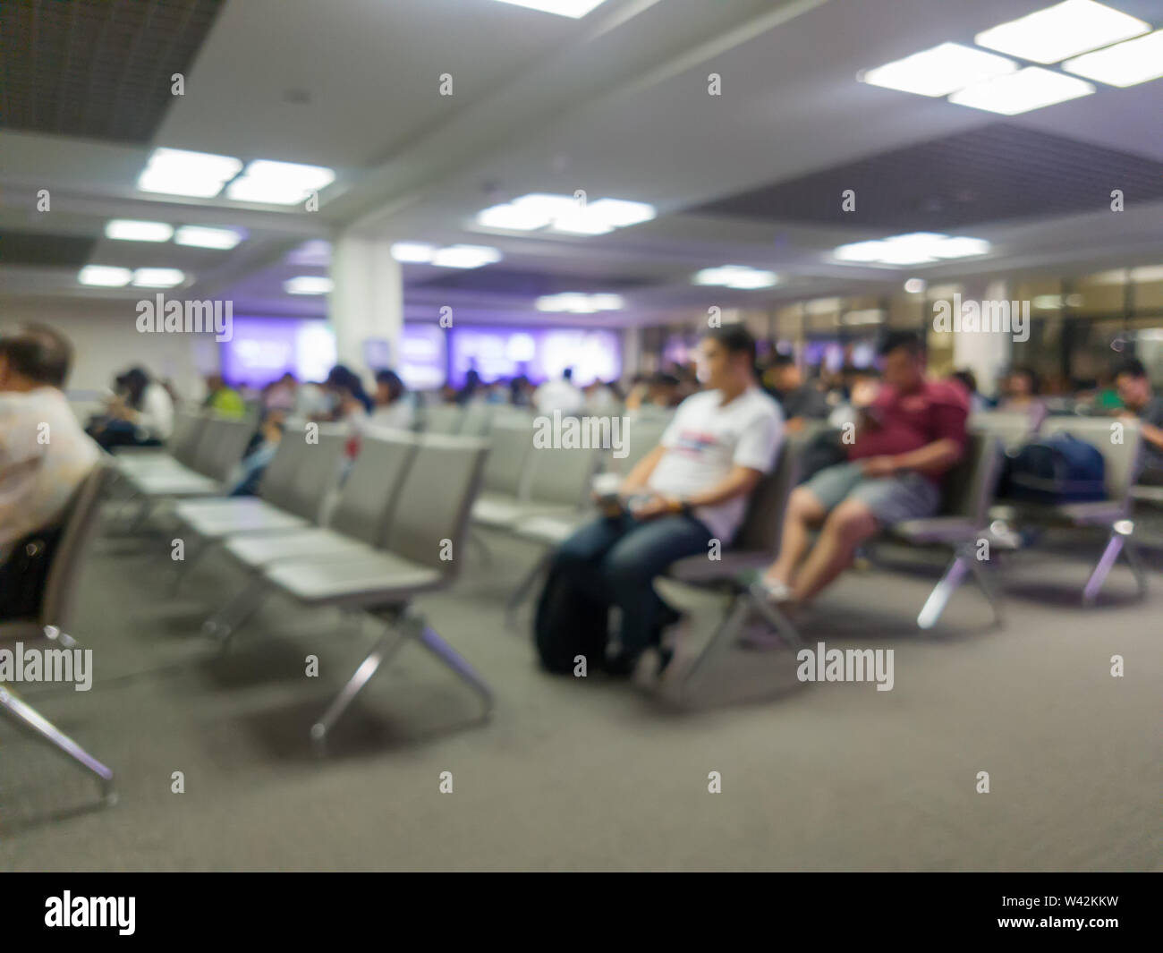 Flou abstrait des passagers assis à l'aéroport d'embarquement pour l'attente sur l'heure d'embarquement Banque D'Images