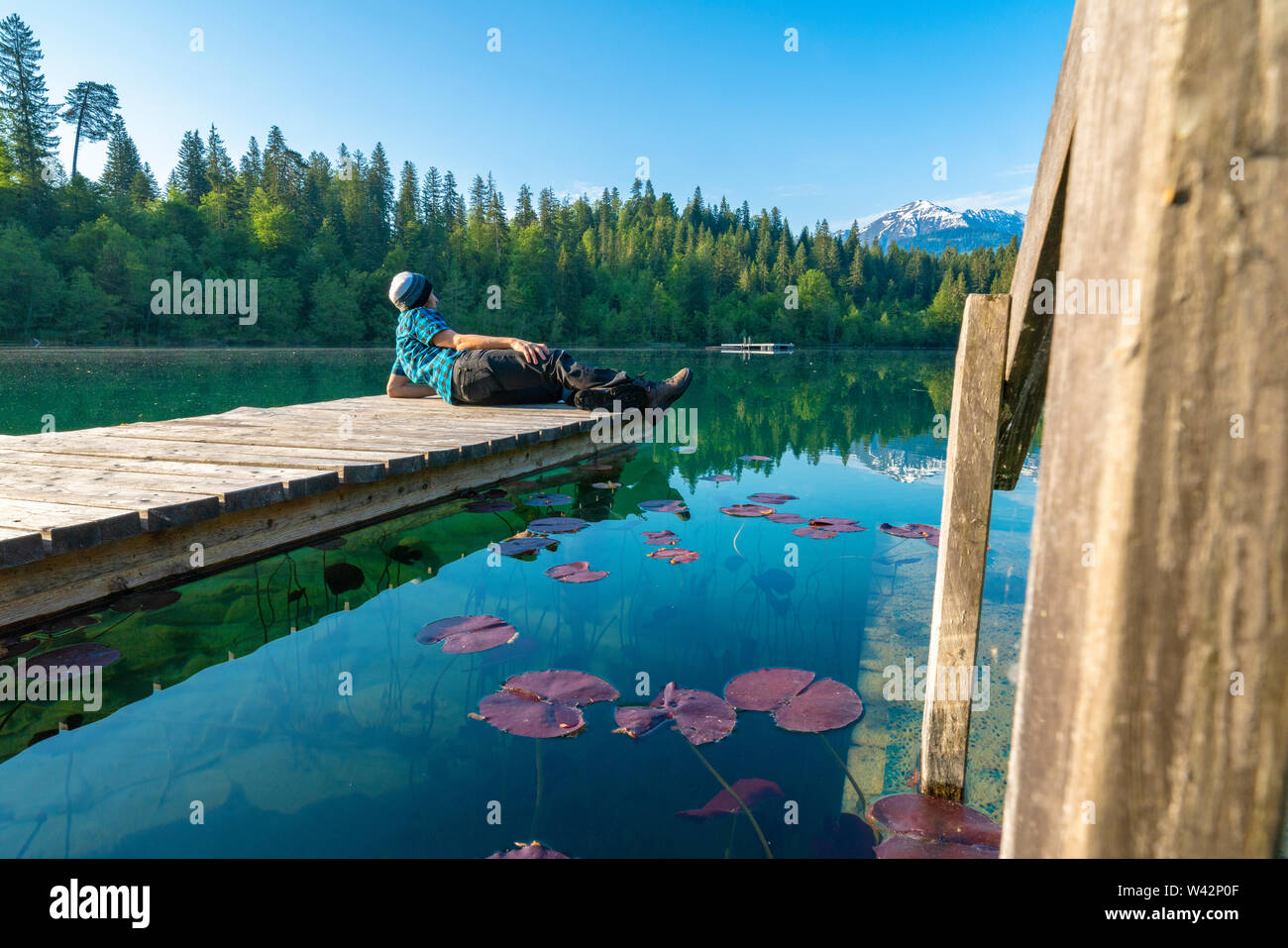 L'homme sur la plate-forme de détente en profitant de la vue du lac Cresta (Crestasee), Films, canton des Grisons, Suisse Banque D'Images