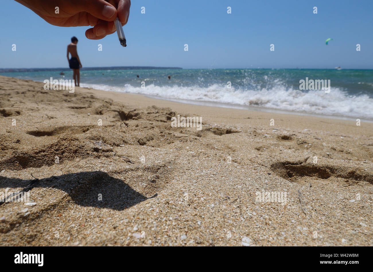 19 juillet 2019, l'Espagne, Palma : une femme est maintenant une cigarette sur la plage de Cala Estancia. Depuis le 17.07.2019 il y a une interdiction de fumer. Jusqu'ici, cependant, il a été seulement une recommandation : les baigneurs qui ne respectent pas l'interdiction ne serait pas puni, du moins pas pour le moment, il a été dit, citant les autorités. Photo : Clara Margais/dpa Banque D'Images