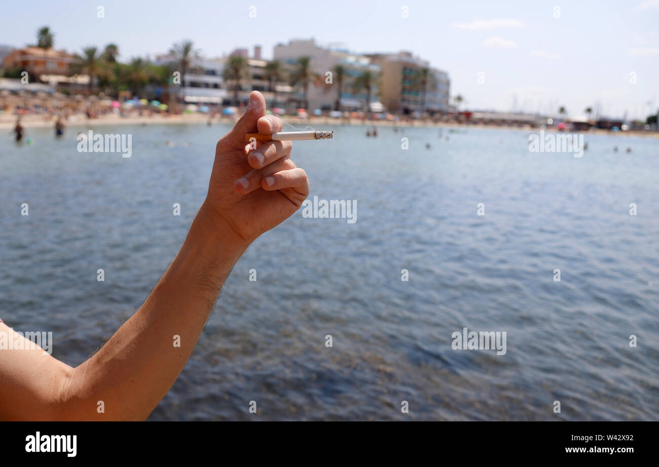 Palma, Espagne. 19 juillet, 2019. Une femme tient une cigarette sur la plage de Cala Estancia. Depuis le 17.07.2019 il y a une interdiction de fumer. Jusqu'ici, cependant, il a été seulement une recommandation : les baigneurs qui ne respectent pas l'interdiction ne serait pas puni, du moins pas pour le moment, il a été dit, citant les autorités. Credit : Clara Margais/dpa/Alamy Live News Banque D'Images