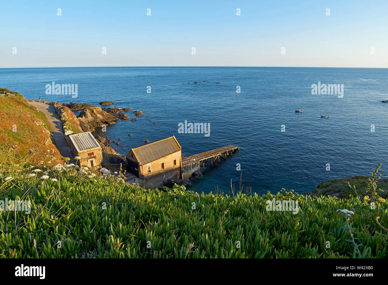 Vue depuis la falaise au-dessus de l'ancienne station de sauvetage de lézard en mer à Polpeor Cove, juste avant le coucher du soleil - péninsule du Lézard, Cornwall Banque D'Images