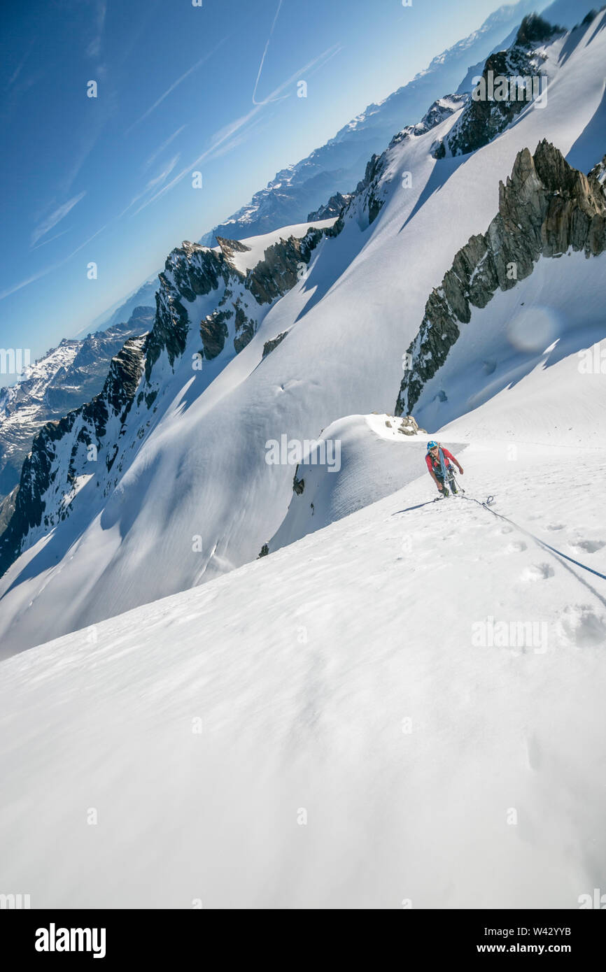 Un alpiniste fait une pause tout en luttant contre une longue et raide montée en France Banque D'Images