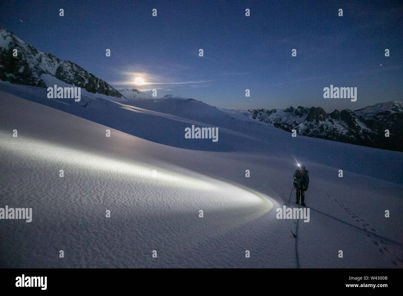 Un alpiniste utilise un projecteur pour naviguer avant aube terrain glaciaire Banque D'Images