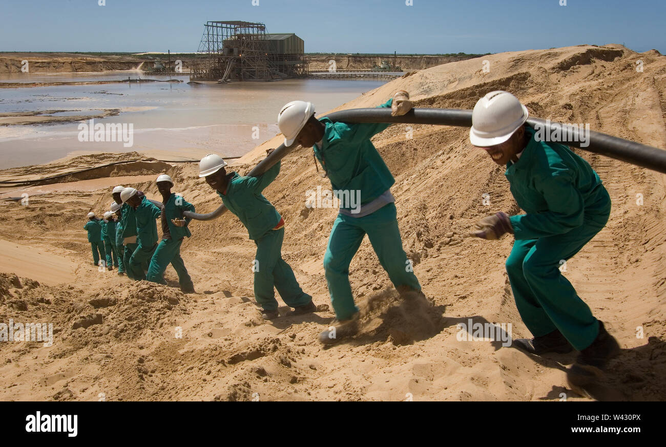 Exploitation minière, gestion et transport des sables bitumineux en titane. L'équipe de maintenance pose de nouveaux câbles d'alimentation sur le côté de l'étang minier pour les installations humides derrière. Banque D'Images