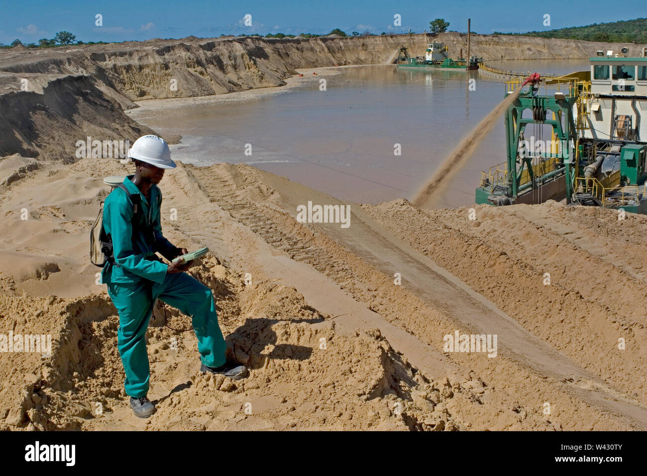 Gestion et transport des sables minéraux de titane sur le site minier. Exploitation minière à l'aide de dragues pompage de sable à partir d'étangs d'eau et d'arpenteur mesurant les hauteurs des dunes. Banque D'Images