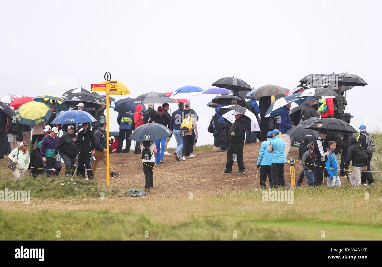 La foule se protéger de la pluie au cours de la deuxième journée de l'Open Championship 2019 au Club de golf Royal Portrush. Banque D'Images