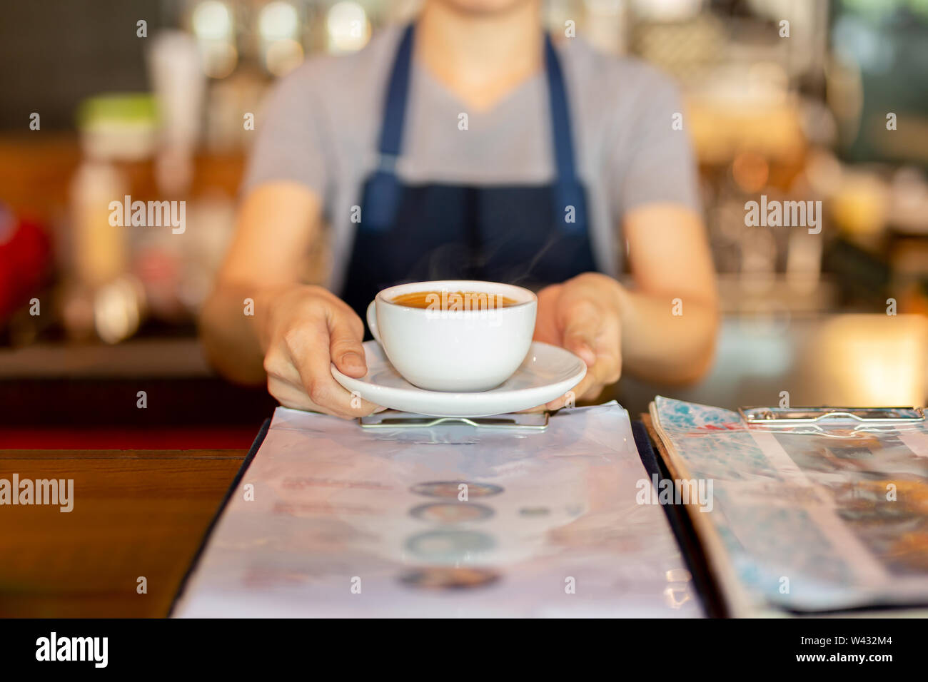 Serveuse servant du café tout en se tenant dans le café au comptoir. Banque D'Images