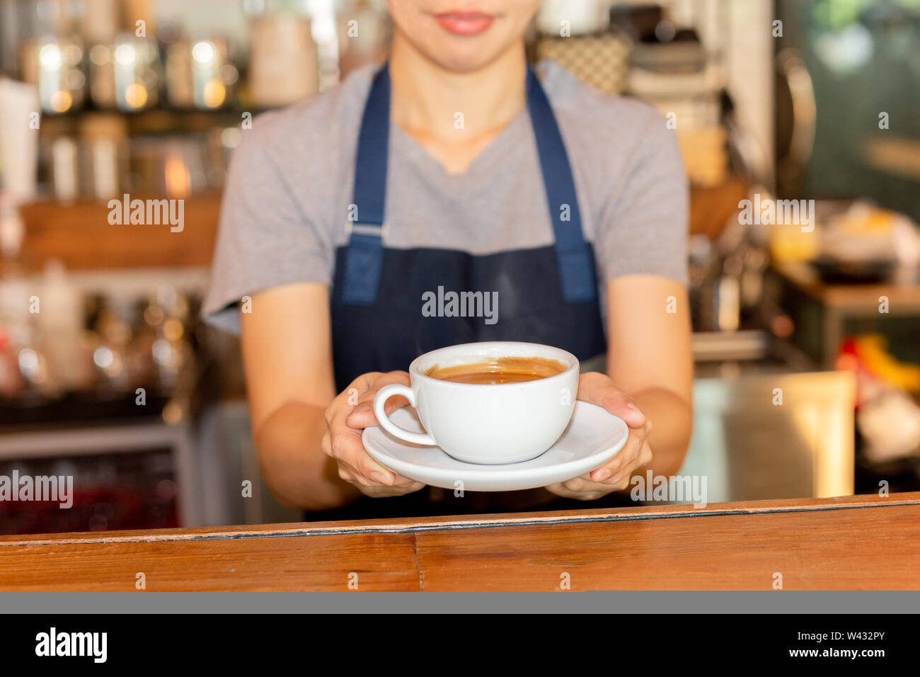 Serveuse servant du café tout en se tenant dans le café au comptoir. Banque D'Images