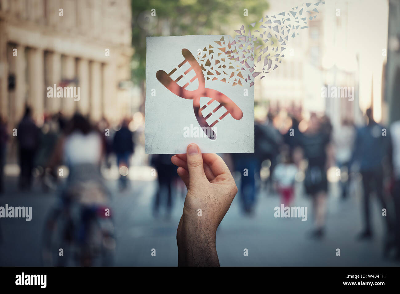 La manipulation génétique et la modification de l'ADN concept comme main de l'homme tenant un papier avec le symbole d'édition de gènes en morceaux sur une rue bondée de retour Banque D'Images