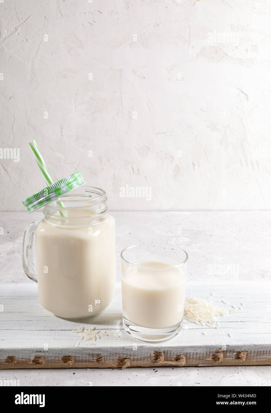 Verre et verre mason tasse avec du lait de riz sain sur planche de bois sur fond blanc. Lait sans lactose concept. Copie de l'image avec l'espace. Banque D'Images