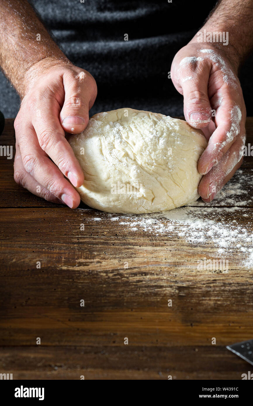 L'homme préparation de pâte à pain sur la table en bois dans une boulangerie close up Banque D'Images