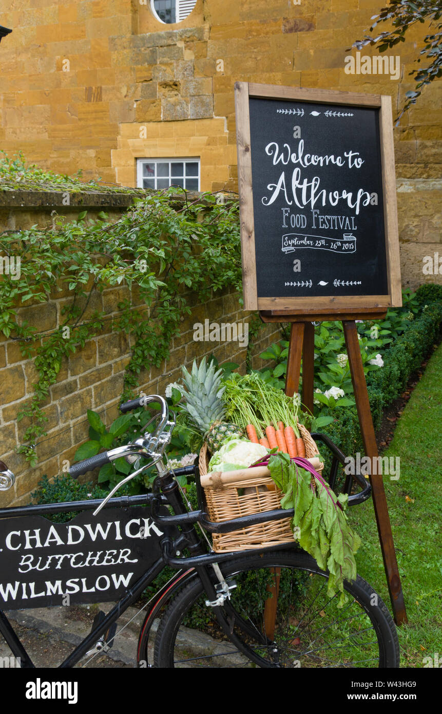 Signe sur un tableau noir l'accueil des visiteurs à l'Althorp Food and Drink Festival, Northamptonshire, Royaume-Uni ; devant une ancienne boucherie vélo avec légumes Banque D'Images