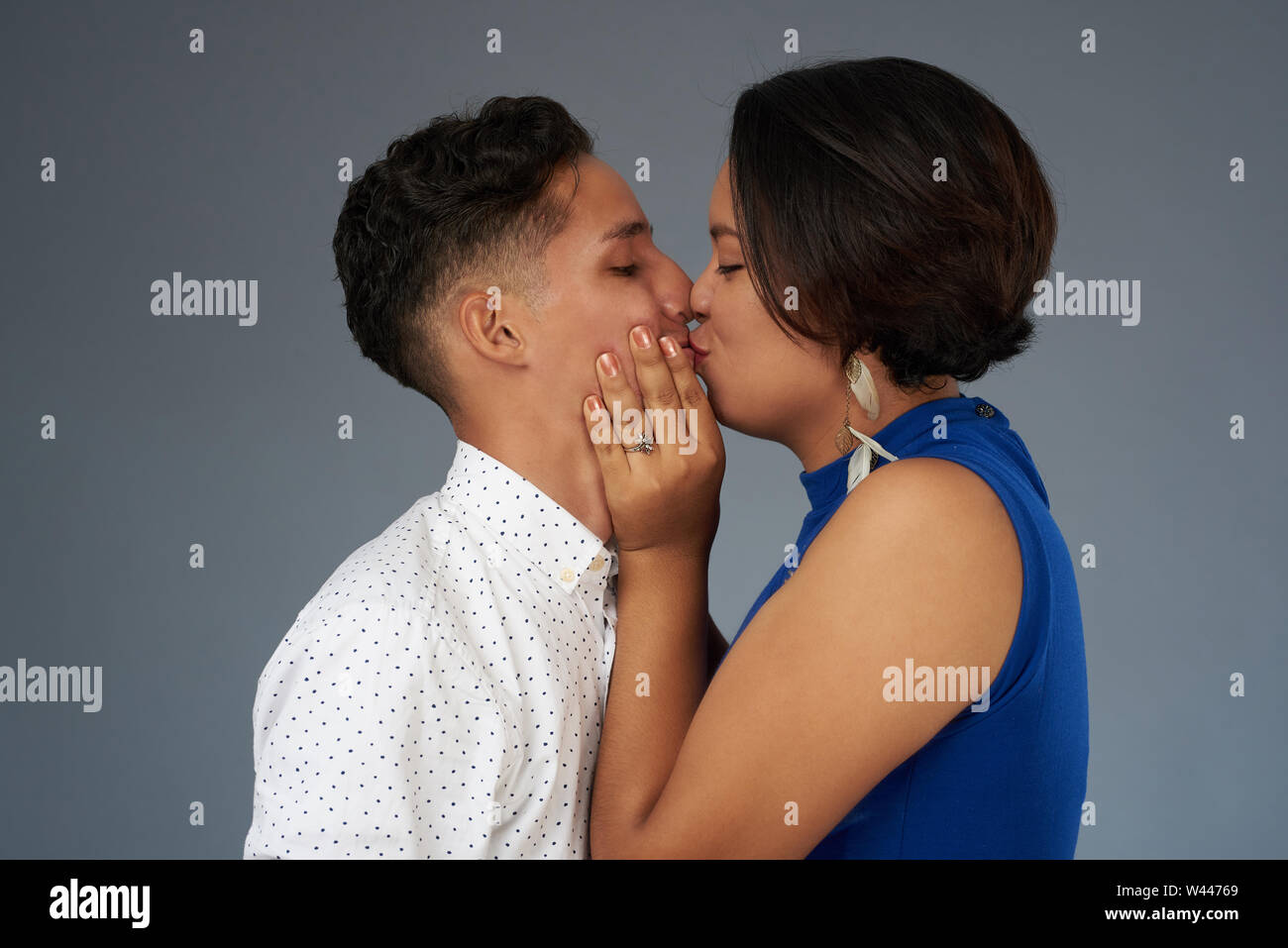 Baiser de jeunes. Hispanic couple kissing on grey background studio Banque D'Images