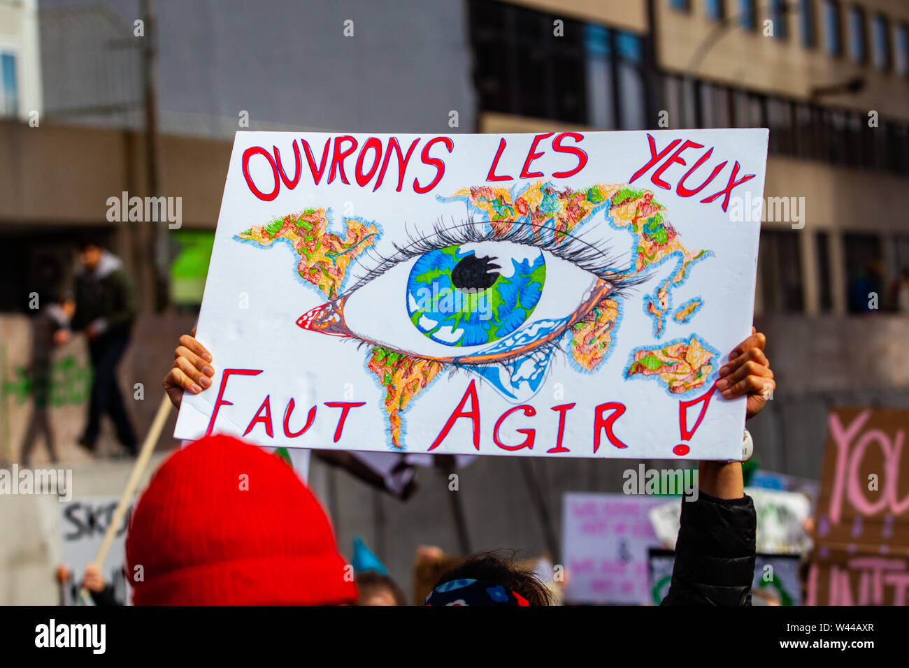 Un gros plan sur une affiche en français faits maison, disant : ouvrez vos yeux, intervenons, tenu par un militant au cours d'une protestation de la rue bondée pour l'environnement. Banque D'Images