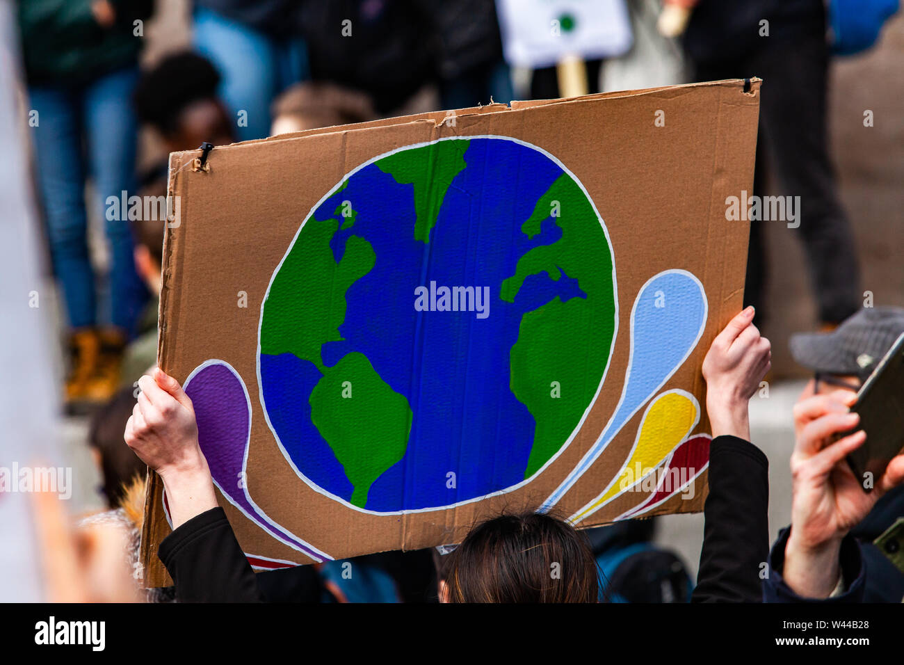 Une affiche représentant la planète terre est vu de près, comme un militant de l'environnement marche contre le changement climatique sur une rue de ville urbaine. Banque D'Images